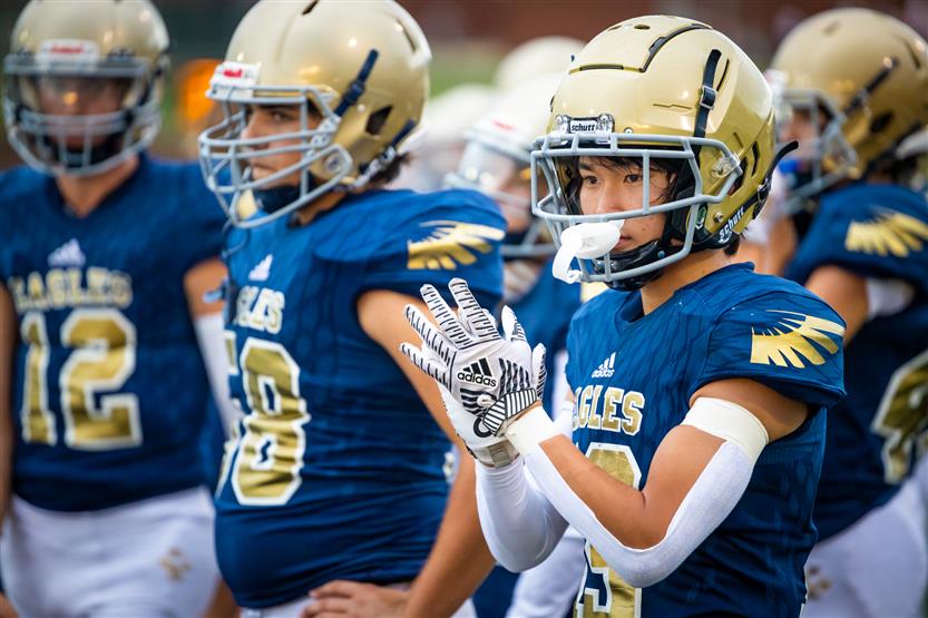 A football player watches the game from the sidelines